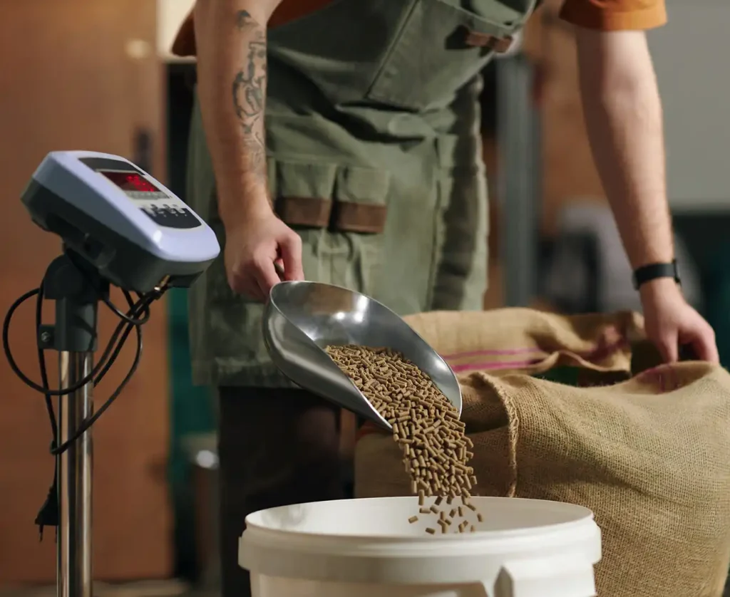 Farmer pouring feed pellets into a plastic bin on a scale for feed formulation measurements at Valley Feed & Supply