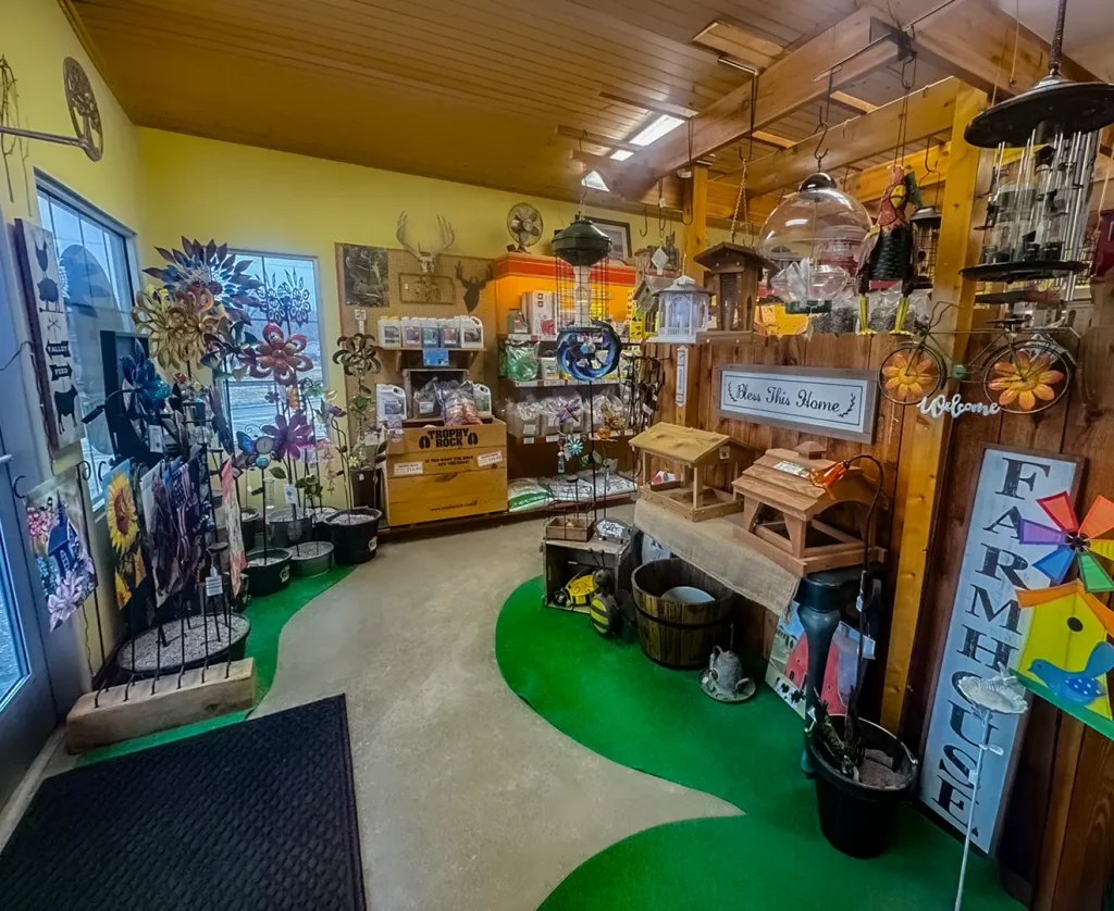 Interior entrance of Valley Feed & Supply store displaying windmills, bird feeders, and farm care products.